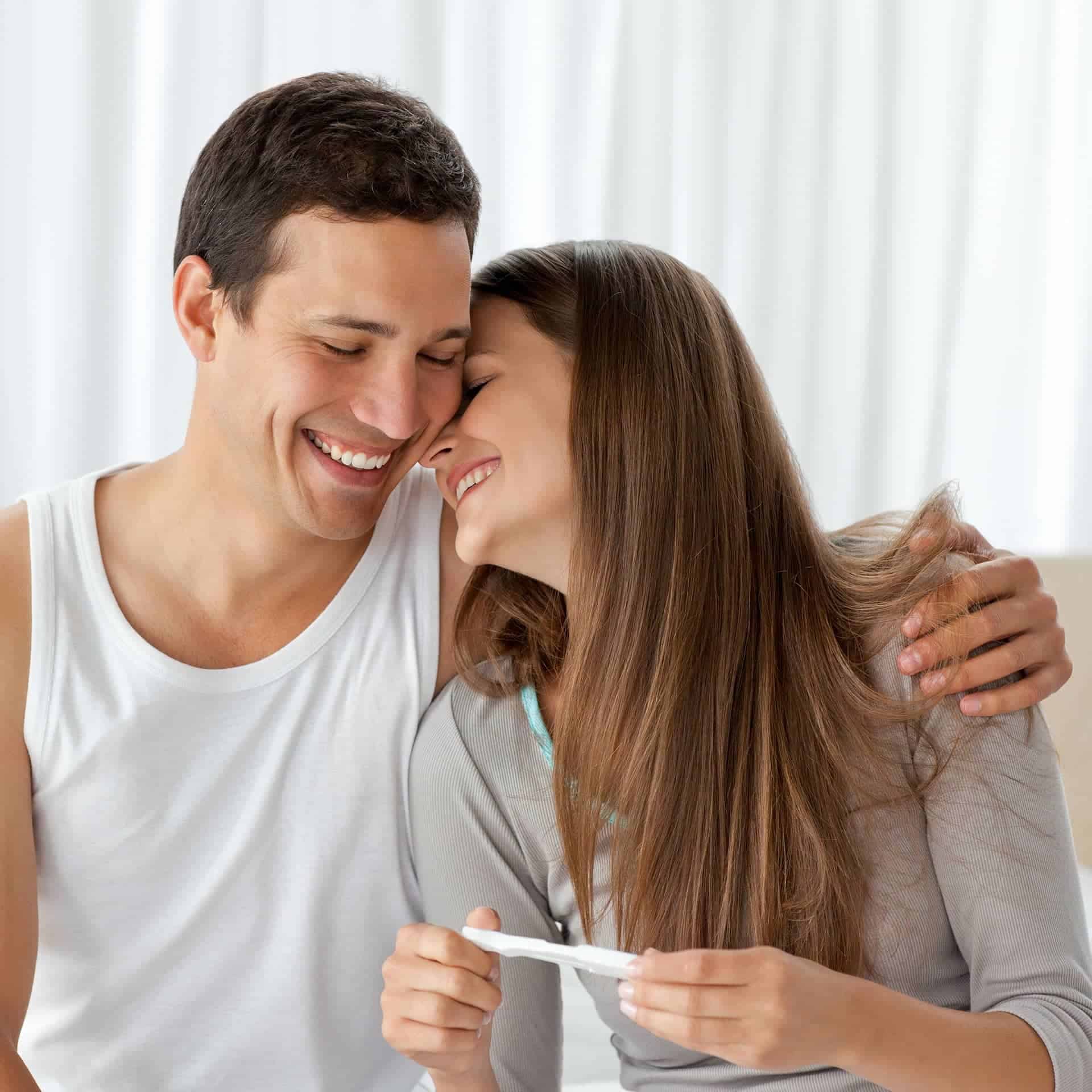 Cheerful couple with a pregnancy test in the bedroom